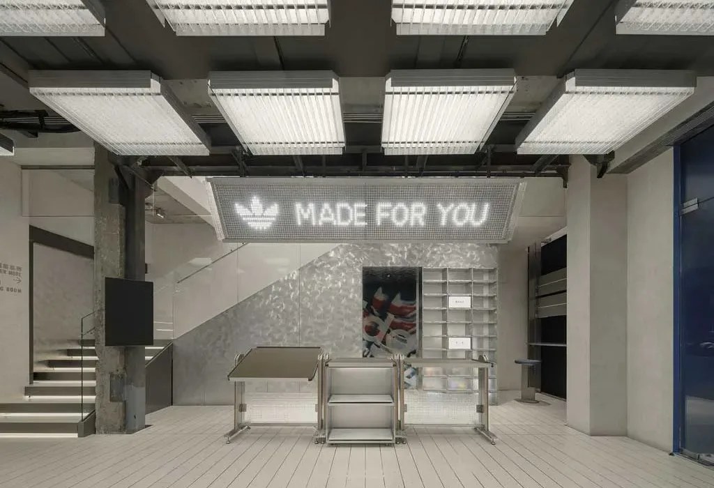 Area personalizzazione del flagship store Adidas Originals a Shanghai con insegna luminosa Made for You e design industriale