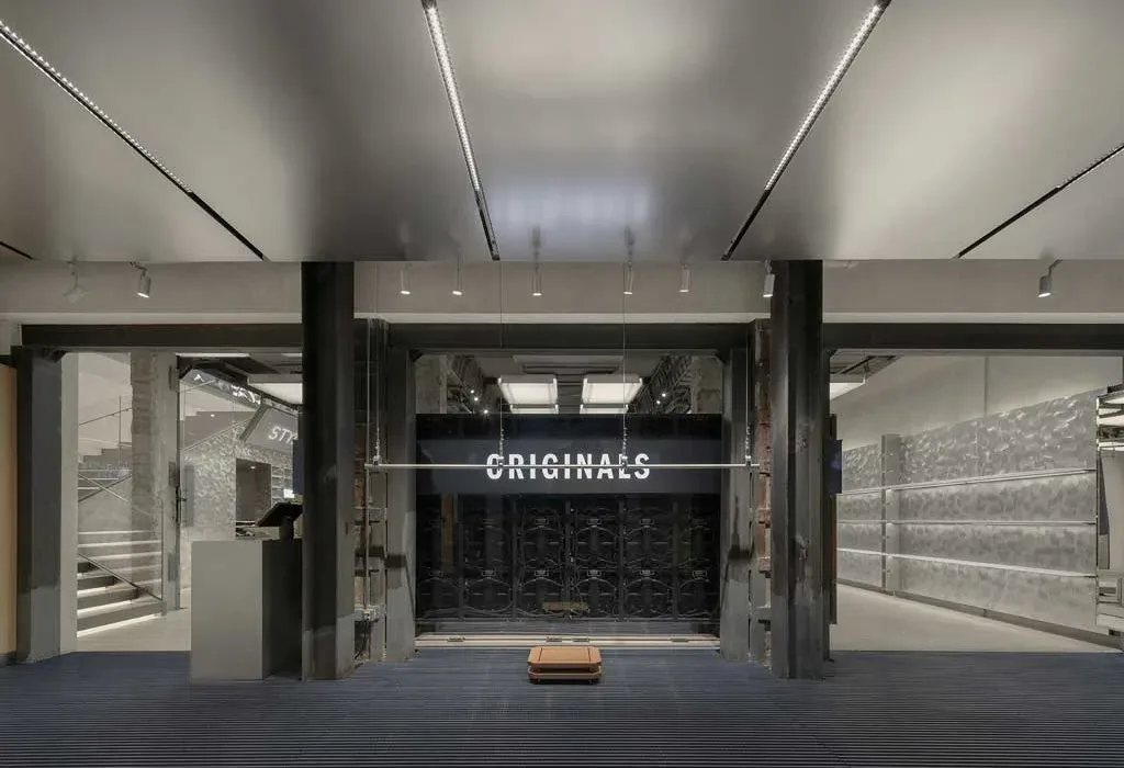 Interno del flagship store Adidas Originals a Shanghai con insegna Originals e materiali grezzi.