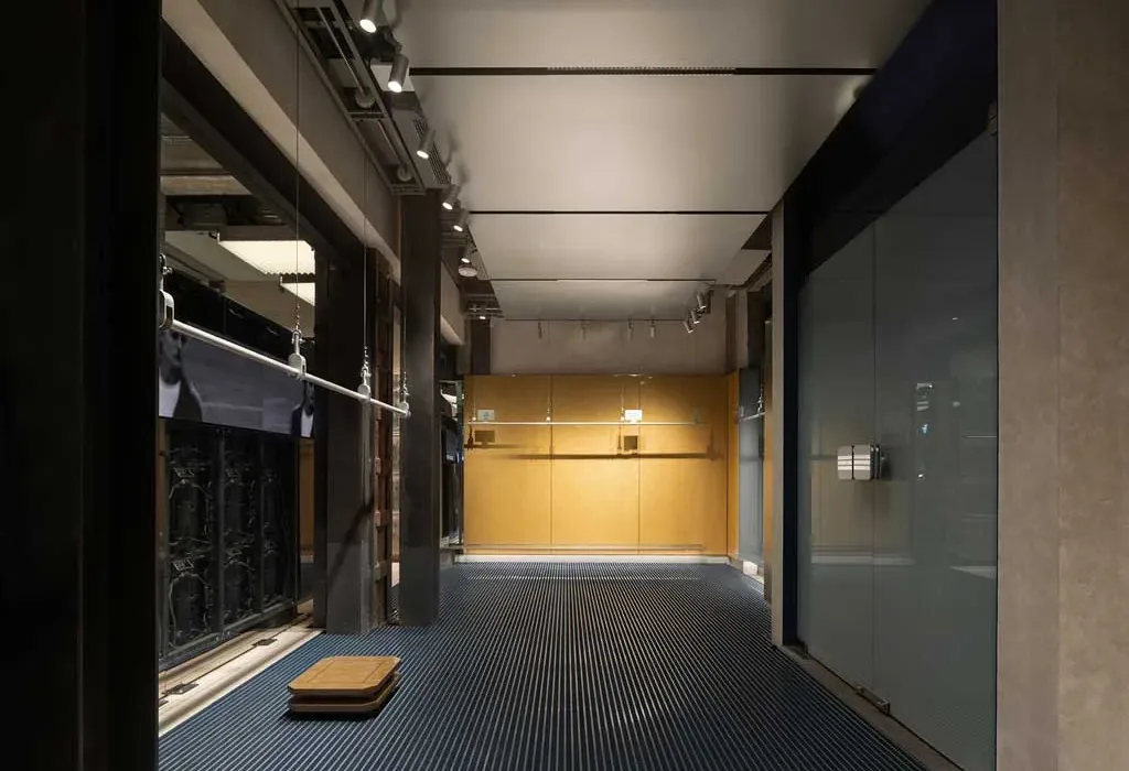 Corridoio espositivo del flagship store Adidas Originals a Shanghai con rivestimenti in vetro e pareti dorate