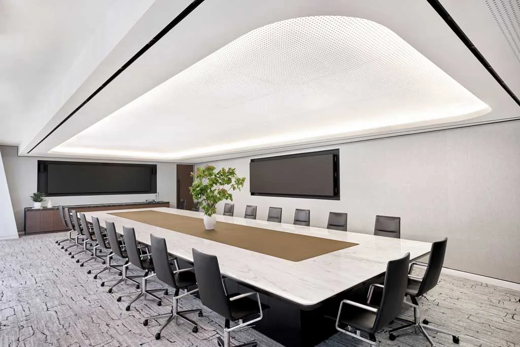 Sala riunioni principale con lungo tavolo in marmo bianco, sedie ergonomiche nere e illuminazione a LED integrata presso l'HSBC Zero Carbon HQ sostenibile.