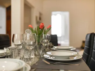 Tavolo da pranzo moderno con sedie imbottite nere, mise en place elegante e tulipani rossi come centrotavola – tendenze living 2025