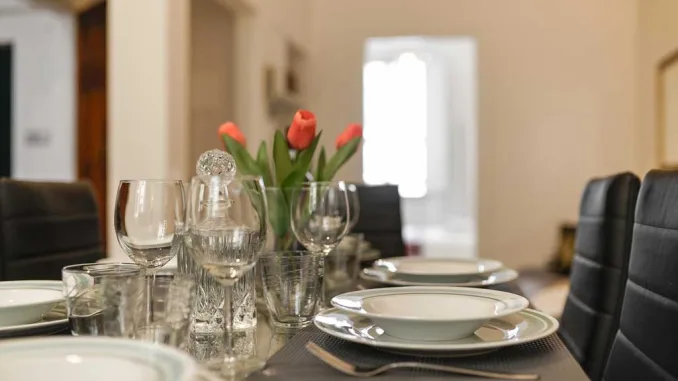 Tavolo da pranzo moderno con sedie imbottite nere, mise en place elegante e tulipani rossi come centrotavola – tendenze living 2025