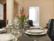 Tavolo da pranzo moderno con sedie imbottite nere, mise en place elegante e tulipani rossi come centrotavola – tendenze living 2025