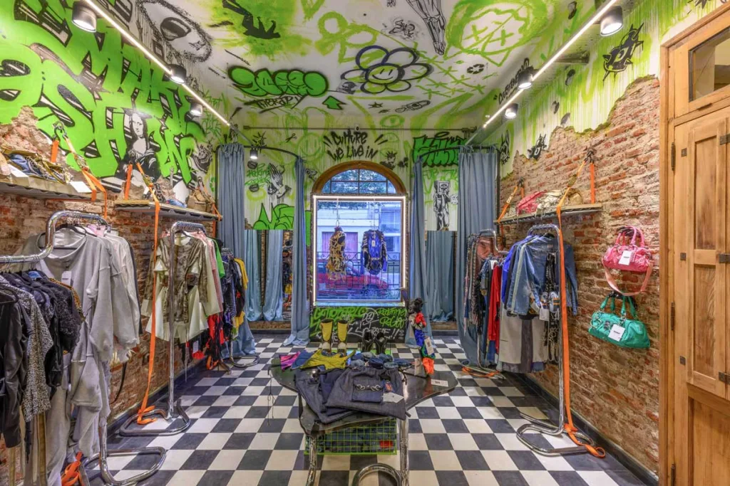 Interno Therapy store con graffiti verdi e abiti riciclati esposti su tubolari metallici