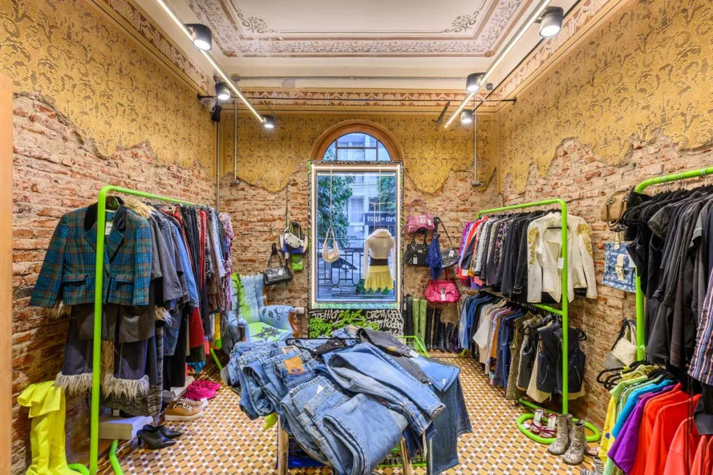 Area vintage del concept store Therapy con abiti e accessori su espositori verdi