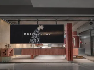 Vista esterna del RUI SPACETIME Concept Store a Shenzhen con facciata in vetro, rivestimenti in travertino rosso e installazione multimediale