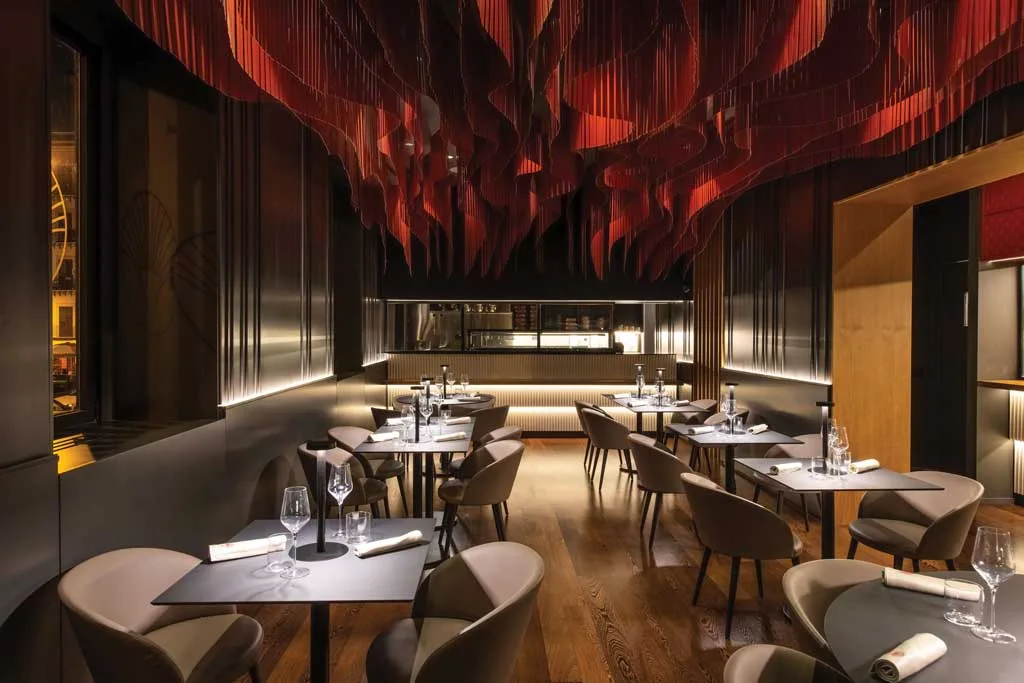 Main dining room of HIO Sushi Lab in Palermo with a striking red wave-like ceiling installation and open kitchen.