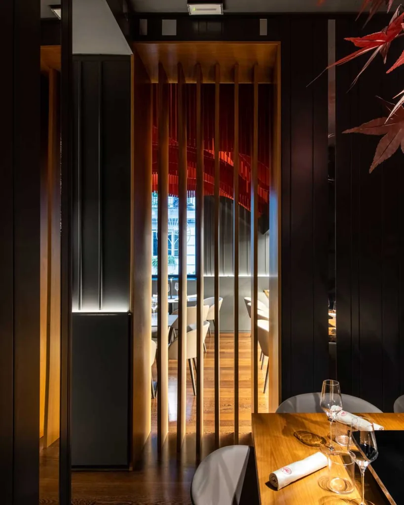 Private room of HIO Sushi Lab in Palermo, full-height wooden partitions with light effects and set dining table.