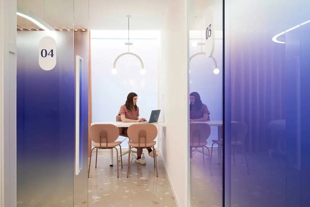 Studio consulenze Visage Clinic con pareti vetrate sfumate, arredo rosa e design cliniche odontoiatriche moderne.