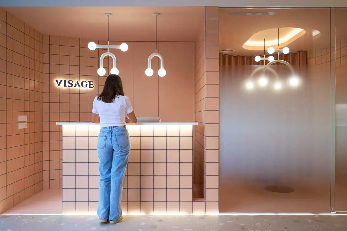 Reception Visage Clinic arredamento cliniche dentali moderne, bancone rivestito in ceramica salmone e lampade sospese di design.