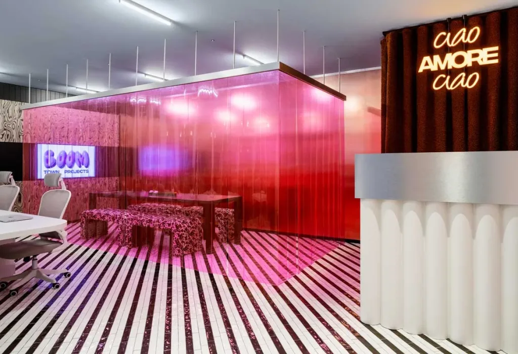 Interno di Boom Town Projects a Grumo Nevano, tra tenda rosa, pavimento optical e scritta luminosa “Ciao Amore Ciao”