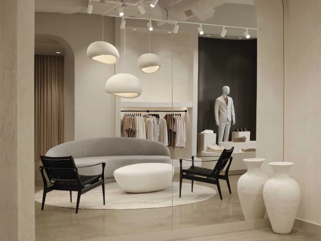 Lounge della Boutique Klozet a Moncton con divano curvo grigio, poltrone nere e lampade sospese organiche