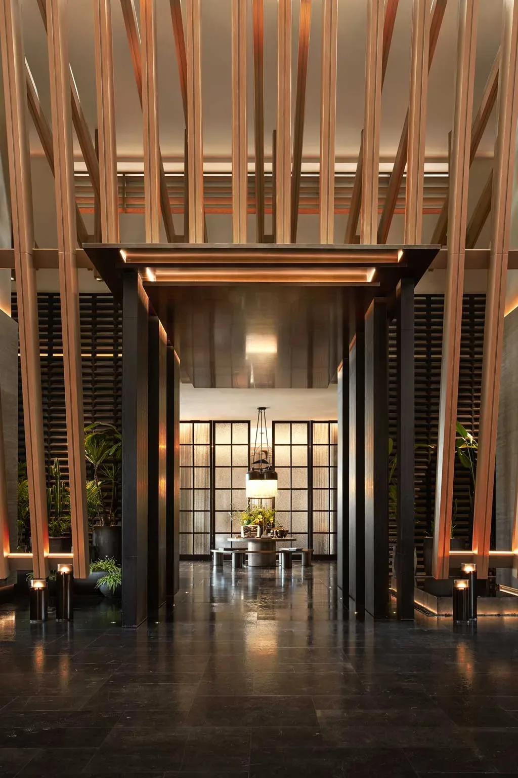 Ingresso principale del Kimpton Aqeos Hainan con struttura architettonica in bronzo e luce naturale filtrata.