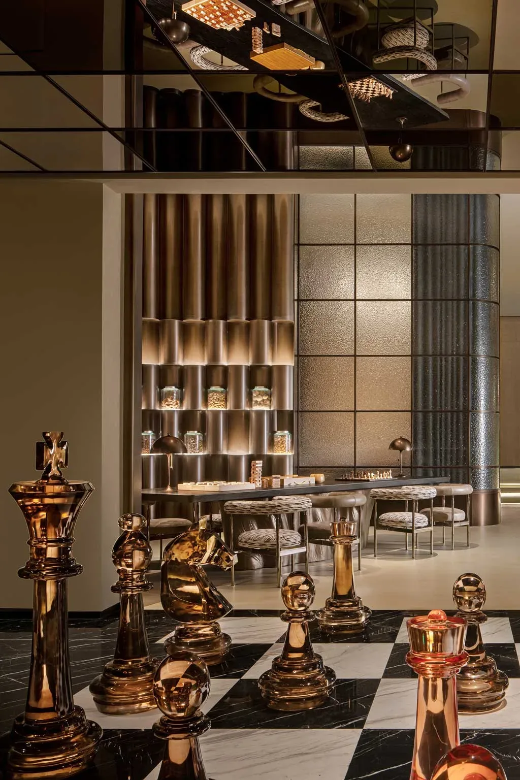 Sala giochi del Kimpton Aqeos Hainan con scacchiera gigante e tavolo per giochi da tavolo in bronzo.
