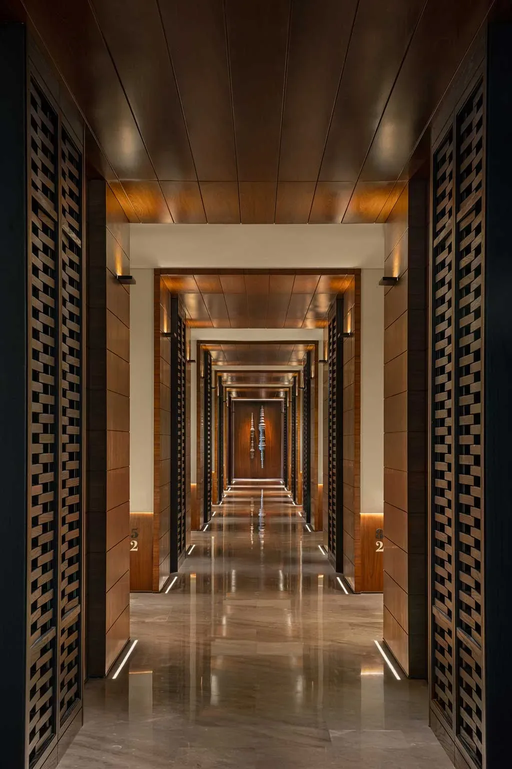 Corridoio del Kimpton Aqeos Hainan con pannelli in legno e illuminazione radente.