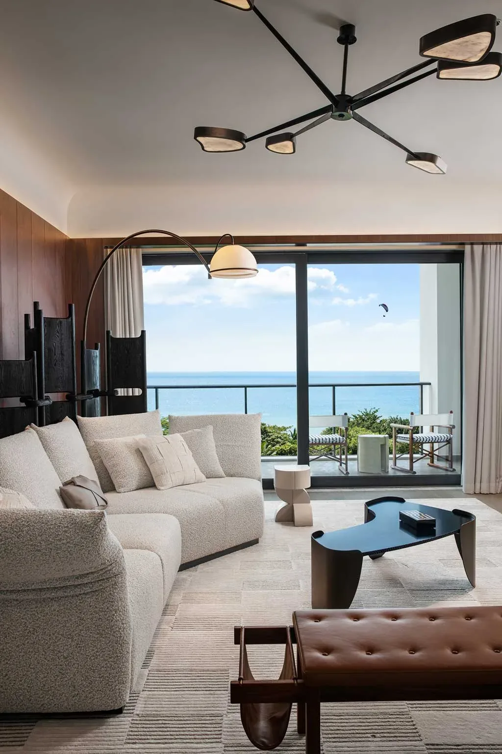Suite del Kimpton Aqeos Hainan con vista sull’oceano e arredi contemporanei dai toni neutri.