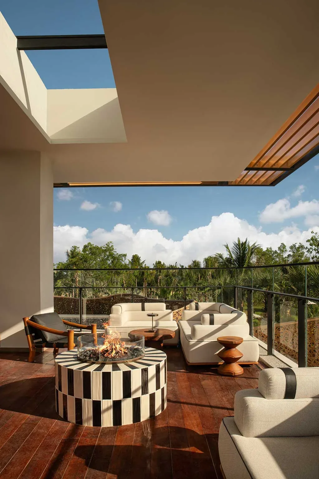 Terrazza panoramica del Kimpton Aqeos Hainan con camino centrale e salotto all’aperto immerso nel verde.
