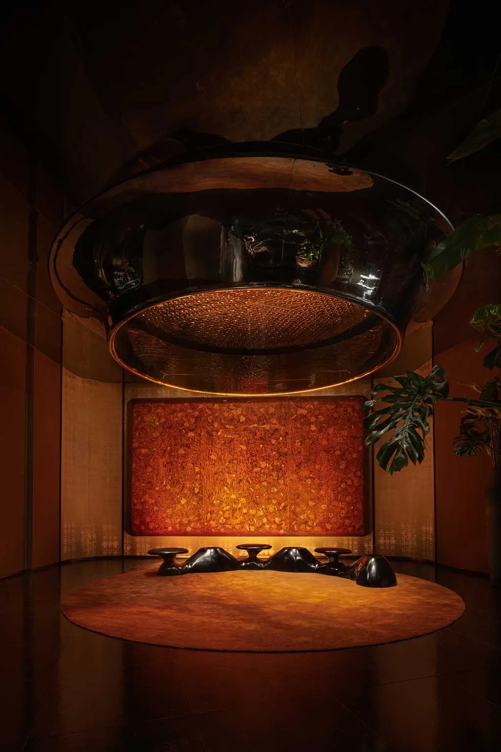 Area lounge del Kimpton Aqeos Hainan con installazione artistica e pareti rivestite in rame.