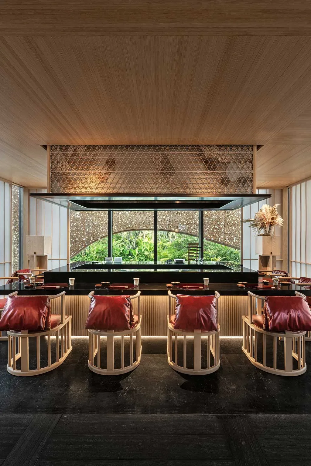 Ristorante giapponese del Kimpton Aqeos Hainan con sedute in legno e vista sulla vegetazione tropicale.