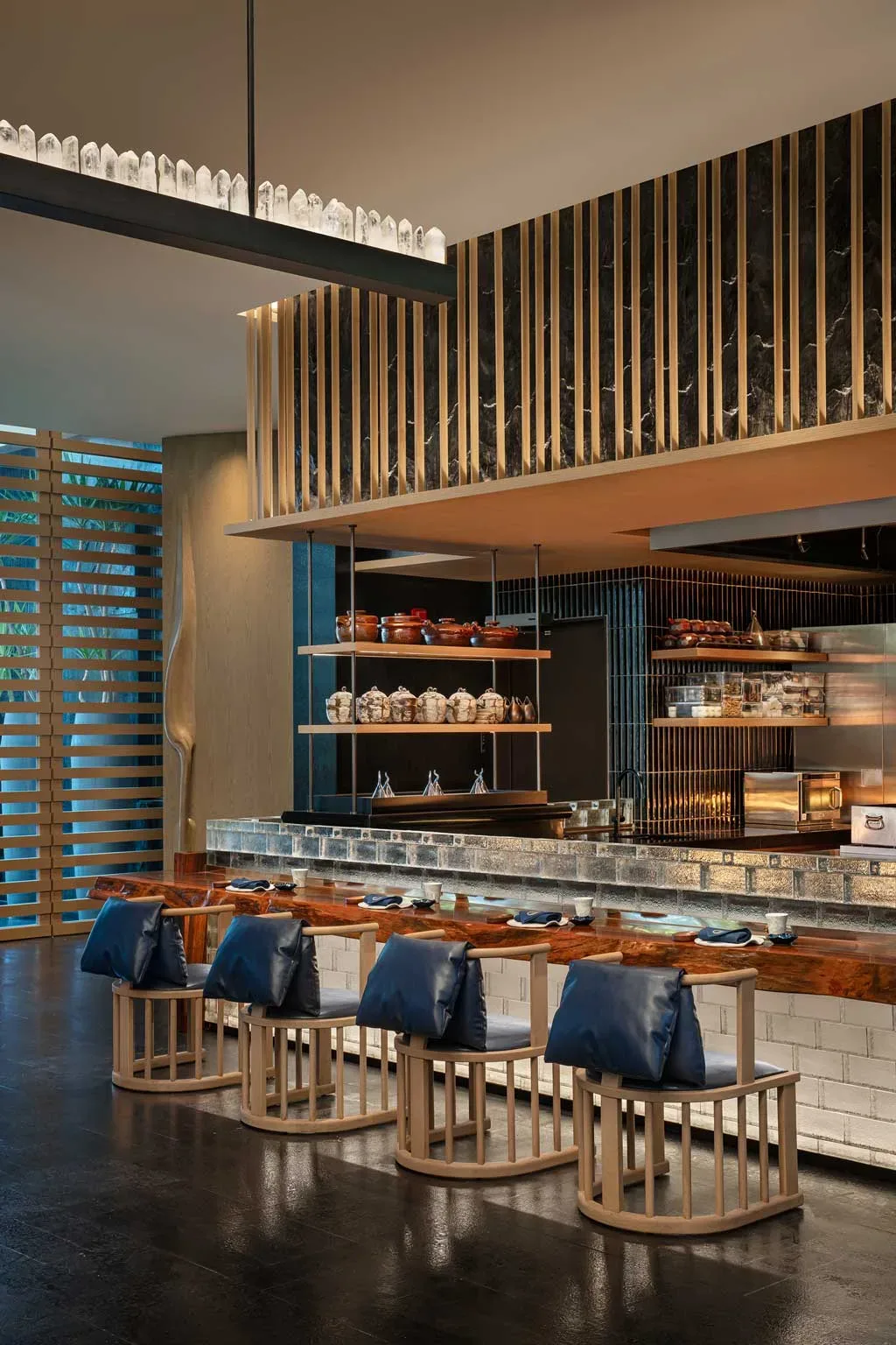 Dettaglio del ristorante del Kimpton Aqeos Hainan con bancone in legno e decorazioni geometriche dorate.