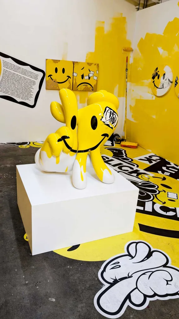 Scultura gialla di OG Slick con smiley stilizzato, parte della mostra immersiva a Los Angeles con grafiche realizzate tramite Mimaki e Drytac