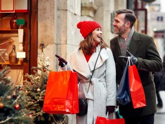 coppia felice con borse colorate mentre fa shopping natalizio in una via decorata a festa