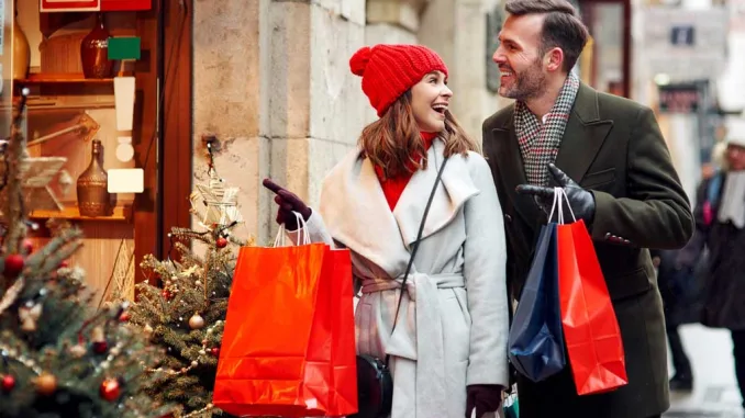 coppia felice con borse colorate mentre fa shopping natalizio in una via decorata a festa