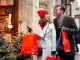 coppia felice con borse colorate mentre fa shopping natalizio in una via decorata a festa