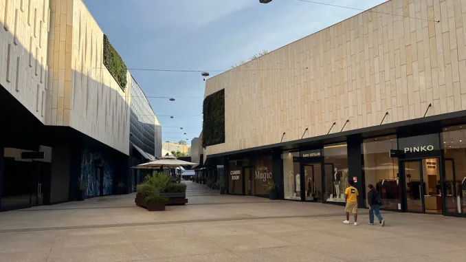 Vista del San Marino Outlet Experience con facciate in pietra chiara, negozi come Pinko e spazi pedonali ampi.