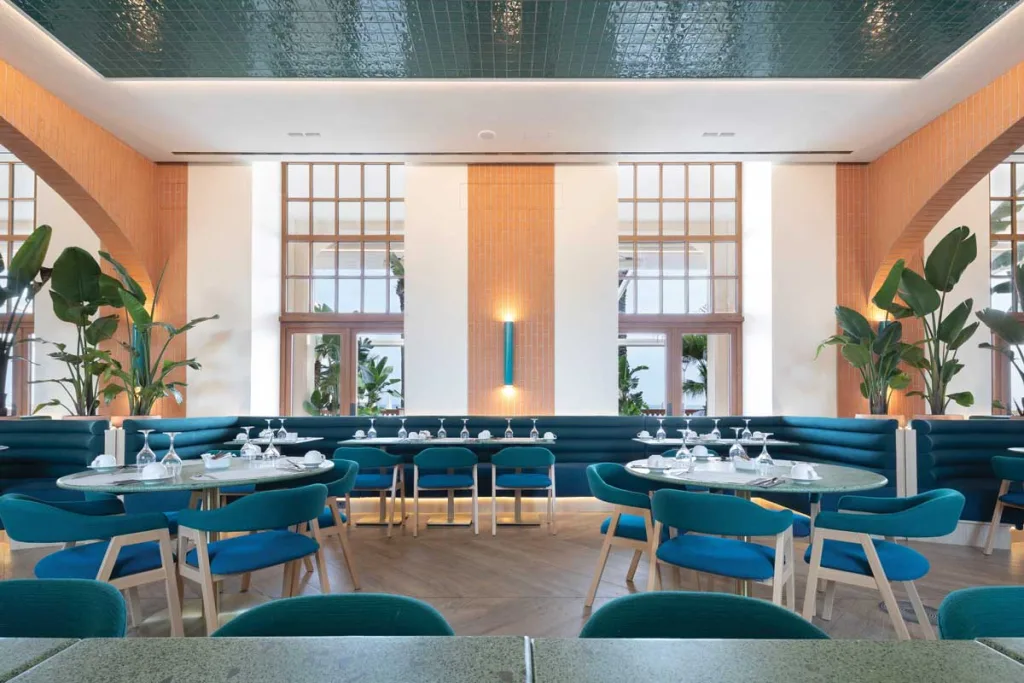 Dettaglio del ristorante La Terrassa del Mar al Le Méridien Ra Beach Hotel & Spa, con arredi in tonalità blu mare, pareti in terracotta e un soffitto riflettente che richiama i riflessi del Mediterraneo