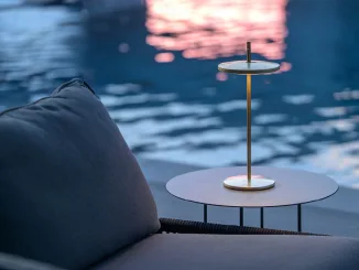 Lampada Thaïs di Platek in ottone con finitura stone washed posata su tavolino outdoor vicino a una piscina al tramonto