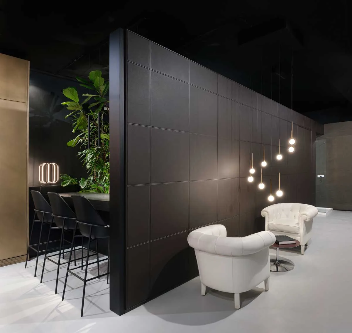 Showroom RiFRA Milano con area lounge, poltrone bianche e parete nera retroilluminata
