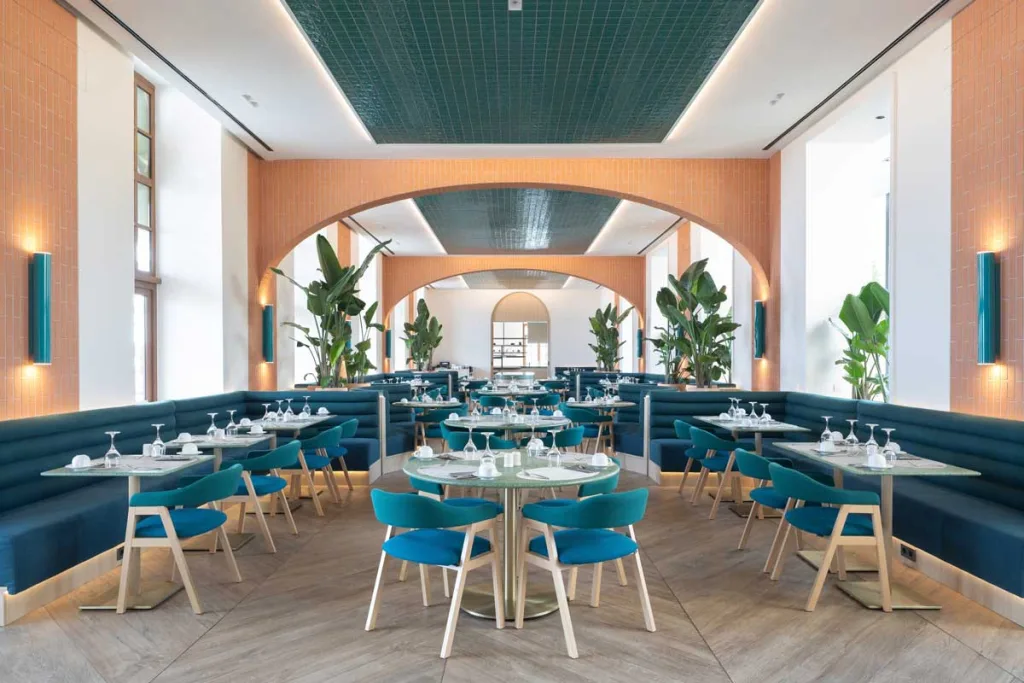 Ristorante La Terrassa del Mar al Le Méridien Ra Beach Hotel & Spa, progettato da Transit Studio con tonalità blu e terracotta, arredi curvilinei e un soffitto riflettente che richiama i colori del Mediterraneo
