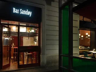 Ingresso illuminato di Bar Sandøy a Milano con vetrina aperta e arredi interni visibili