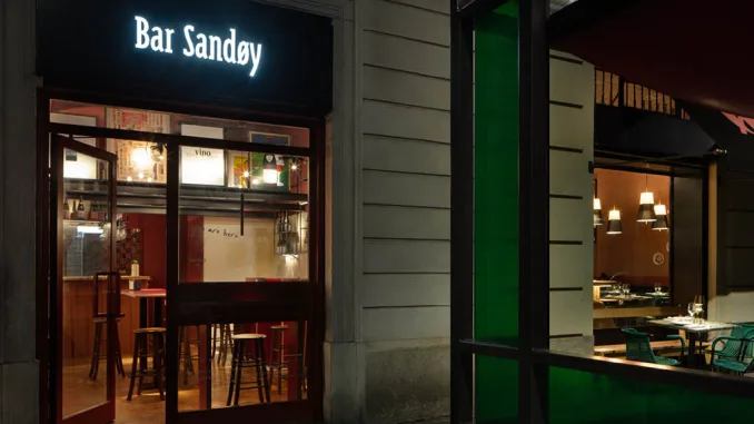 Ingresso illuminato di Bar Sandøy a Milano con vetrina aperta e arredi interni visibili