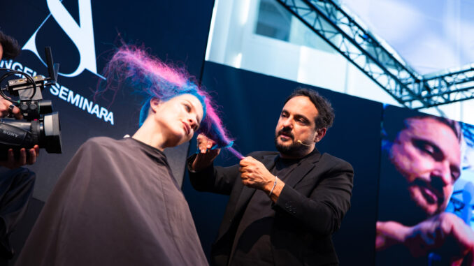 Performance live a On Hair Show: hairstylist lavora su capelli colorati blu e fucsia durante lo show a Cosmoprof Bologna