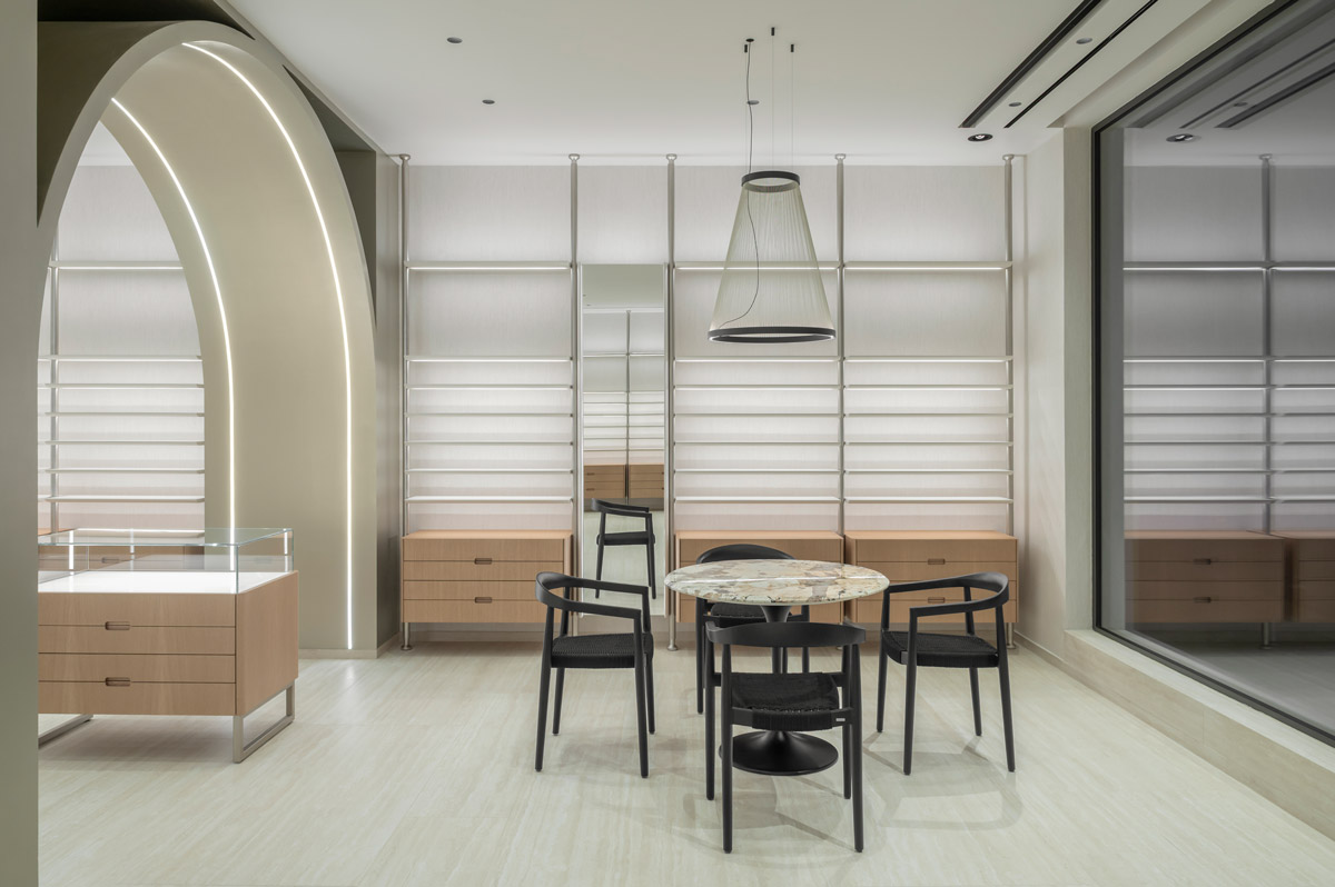 Consultation area with round table, suspended lighting and backlit arch in Optica Alessandro, Ragusa