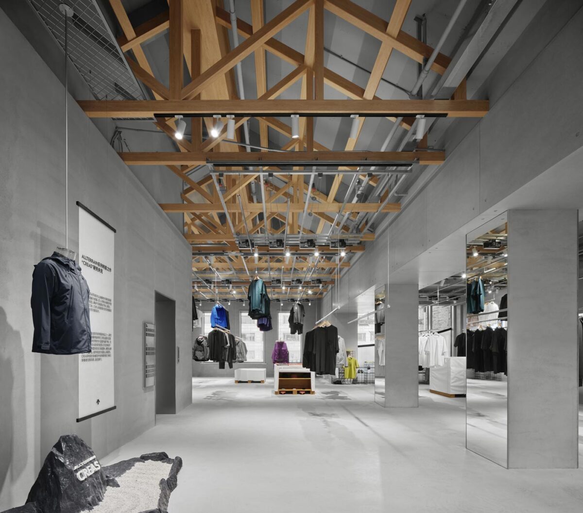 Area espositiva del concept store DESCENTE a Hangzhou con strutture lignee a soffitto e sistema di esposizione sospeso per l’abbigliamento