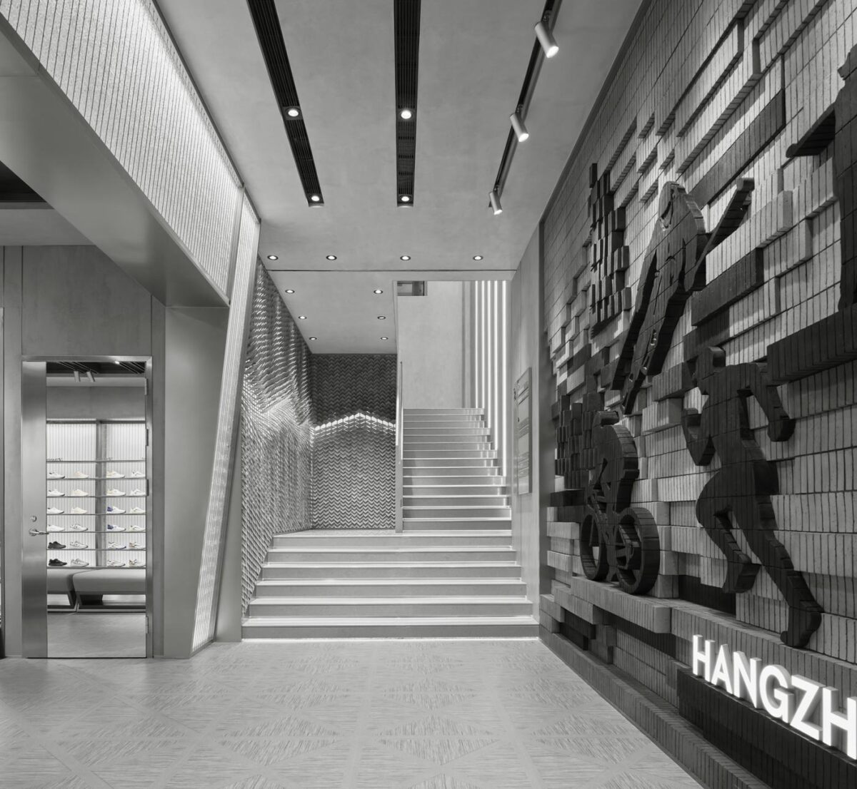 Scala interna del concept store DESCENTE a Hangzhou con parete in mattoni stratificati e illuminazione lineare integrata