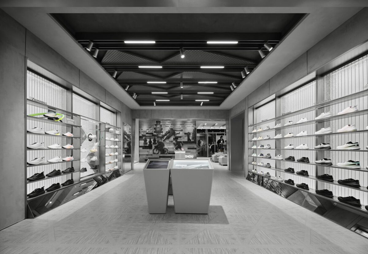 Interni del concept store DESCENTE a Hangzhou con layout simmetrico, pareti espositive per calzature e isole centrali illuminate