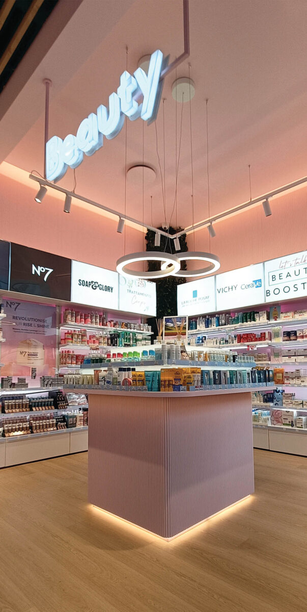 Beauty area of the Boots pharmacy with central island, suspended lighting and pink color palette
