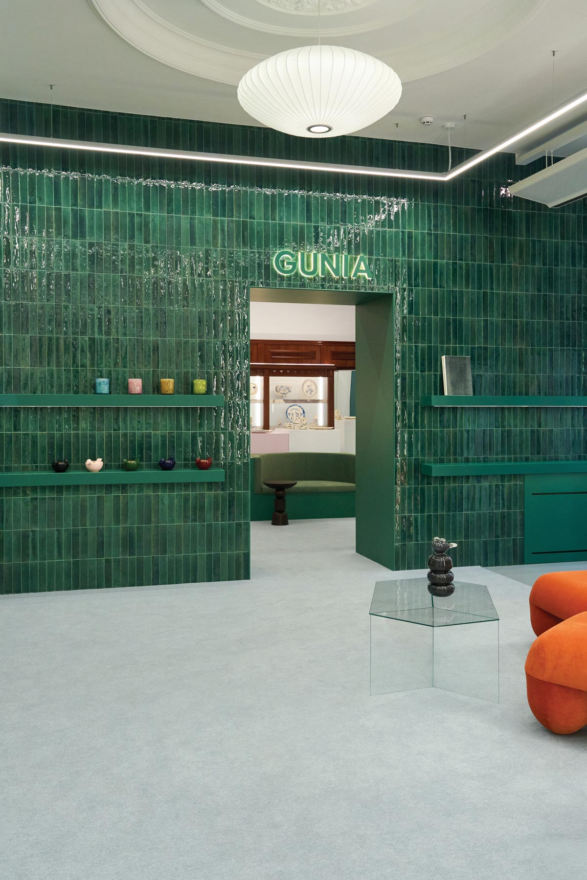 Interior of the GUNIA Project flagship store in Kyiv featuring glossy green ceramic tiles and display shelves for handcrafted ceramics