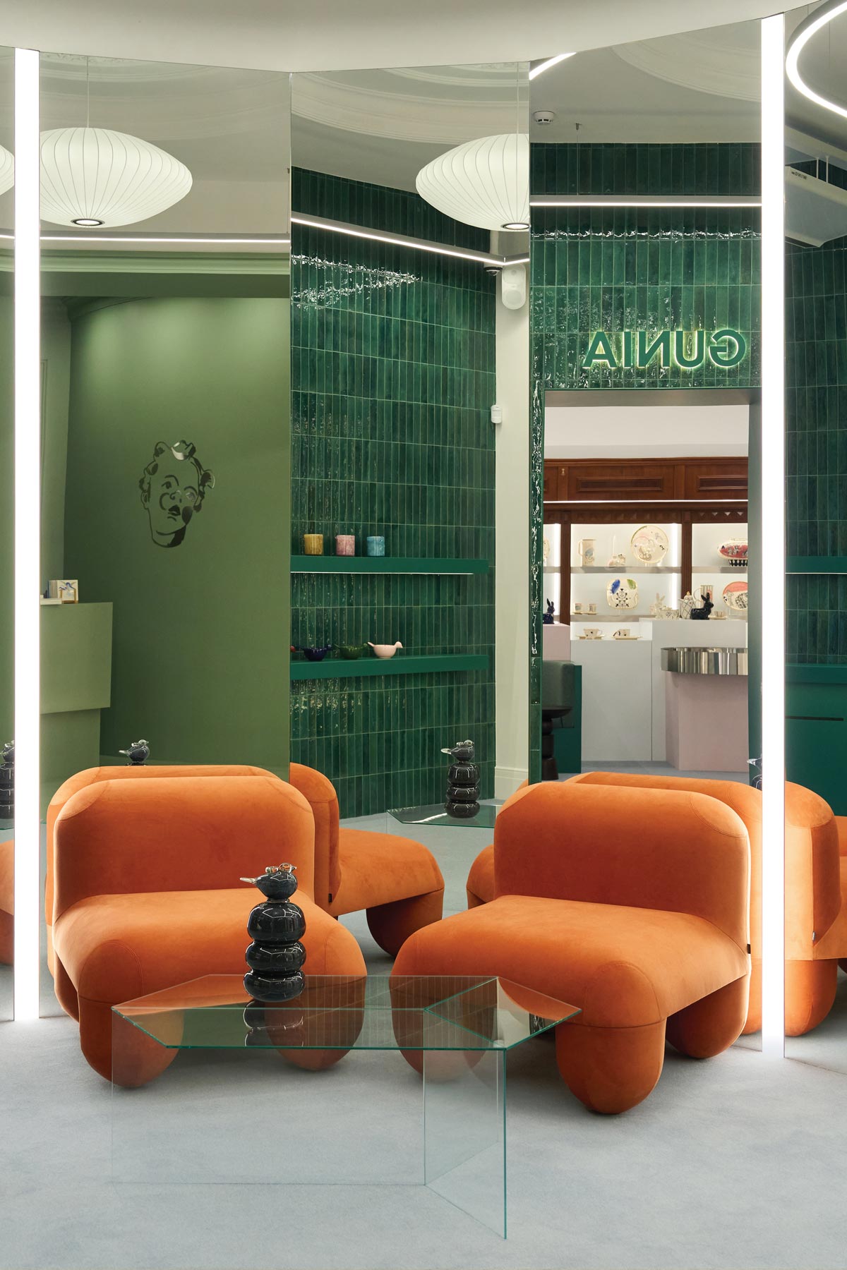 Lounge area of the GUNIA Project flagship store in Kyiv with orange armchairs, mirrored surfaces and ceramic accents