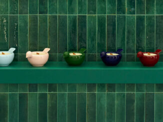 Detail of handcrafted GUNIA Project ceramics displayed on a green shelf against a tiled ceramic wall