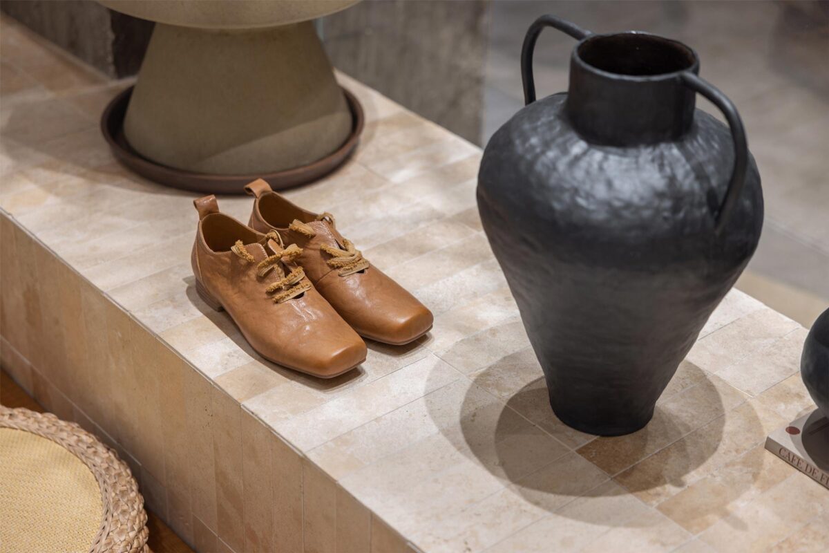 AimeeHe Studio retail store detail in Shenzhen, leather shoes and handcrafted vase on natural stone base highlighting the material palette