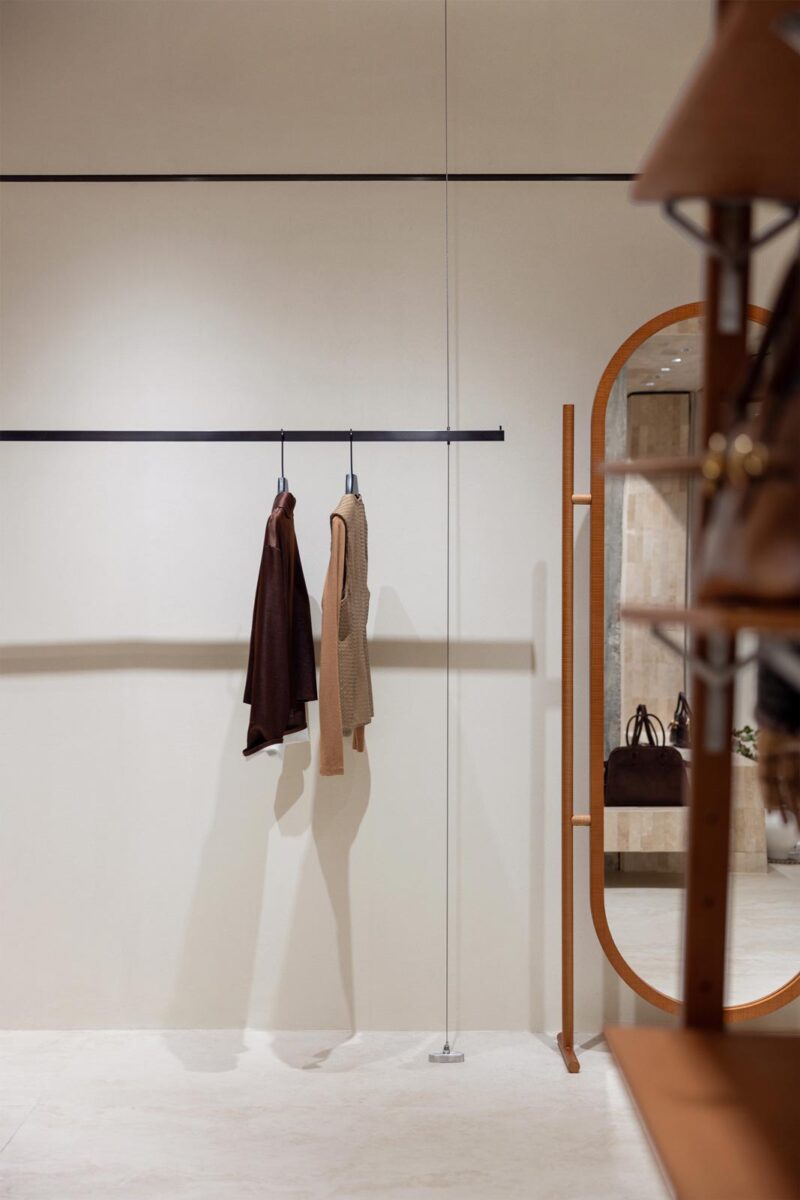 AimeeHe Studio retail store in Shenzhen, minimalist display wall with suspended rails, fashion garments and full-height mirror