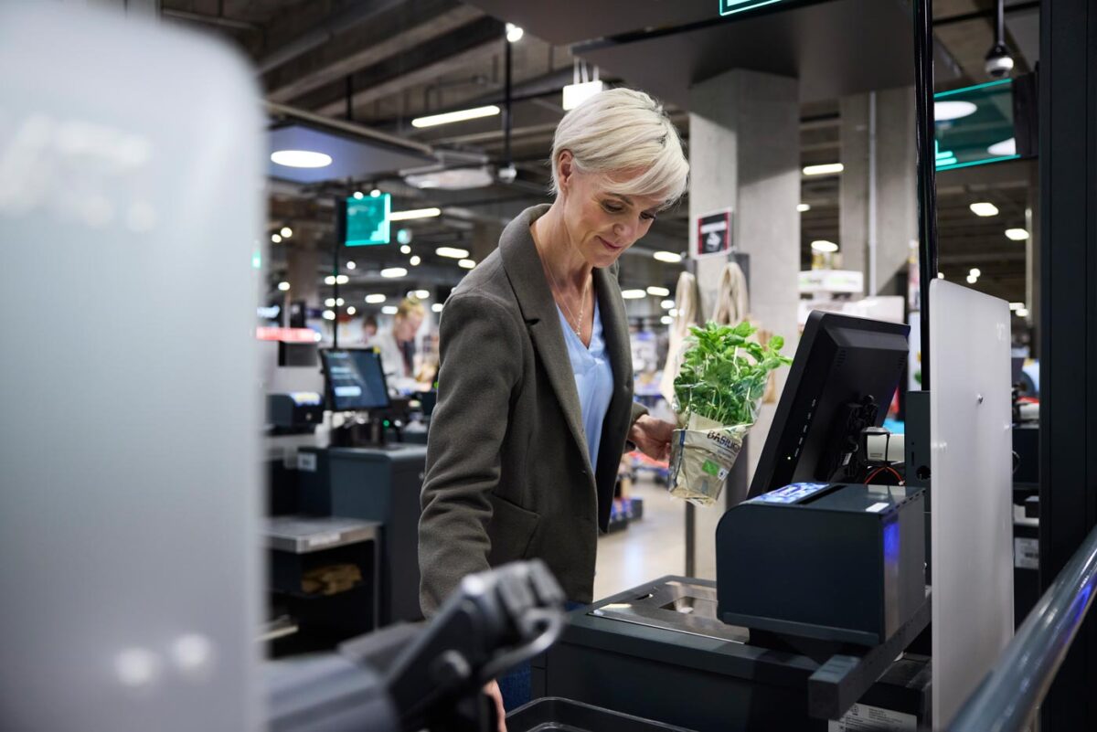 ITAB and HMY together for the first time at EuroShop 2026, customer using self-checkout technology in a modern grocery retail environment with automated payment systems