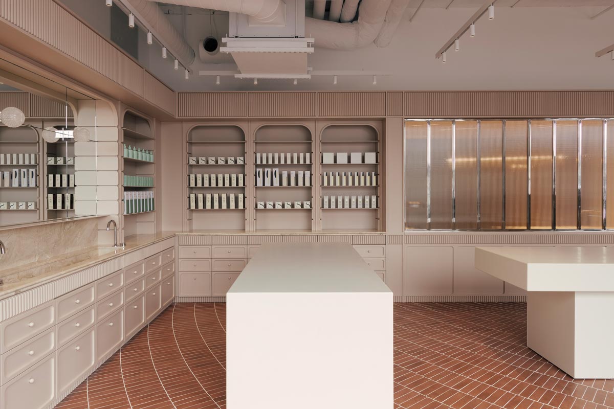 Retail area of the Living Beauty concept store in Toronto featuring a central display table, arched wall niches for product presentation, and terracotta-colored porcelain tile flooring with a concentric pattern.
