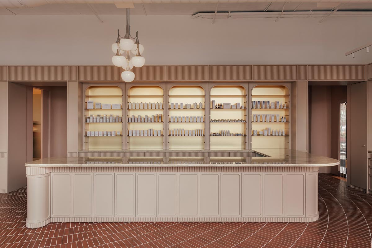 Main counter of the Living Beauty store featuring marble surfaces, integrated lighting, and display walls inspired by historic pharmacy interiors.