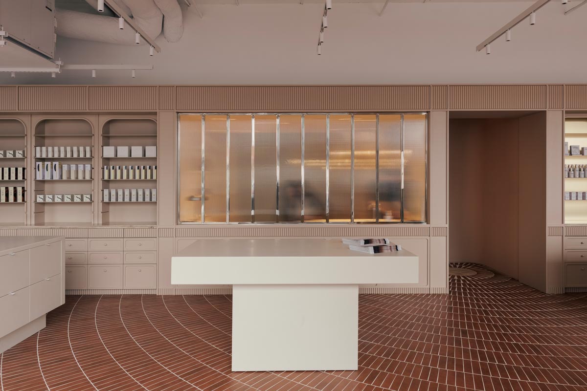 Interior view of the Living Beauty store showing the ribbed glass partition separating the retail area from the spa, with a consultation table and custom-designed furnishings.